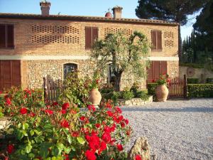 una casa de ladrillo con flores rojas delante de ella en La Piazzetta, en San Gimignano