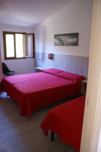 2 camas en una habitación con sábanas rojas en casa mariolu 2 piano mansarda, en Cala Gonone