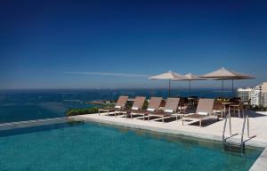 a swimming pool with chairs and umbrellas on a building at Miramar By Windsor Copacabana in Rio de Janeiro