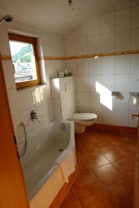 a bathroom with a tub and a toilet and a window at Hotel Gamshof in Kitzbühel