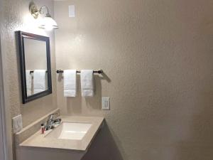 un bagno con lavandino, specchio e asciugamani di Knights Inn Harrisonville a Harrisonville