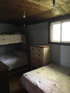 a bedroom with two beds and a dresser and a window at Mowat Landing Cottages in New Liskeard