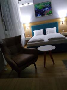 a bedroom with a bed and a chair and a table at NM Apartman in Banja Luka