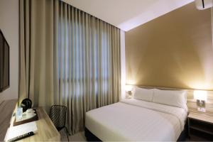 ein Hotelzimmer mit einem Bett, einem Schreibtisch und einem Fenster in der Unterkunft Figtree Hotel in Iloilo City