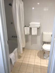 a bathroom with a toilet and a shower stall at Frontier Hotel Darwin in Darwin