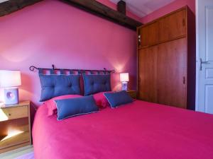 een roze slaapkamer met een groot bed met blauwe kussens bij Charming Holiday Home in Bonnemain overlooking a Pond in Bonnemain