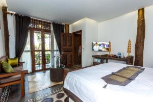 um quarto com uma cama grande e uma televisão em Java Wooden Villa & Residence em Siem Reap