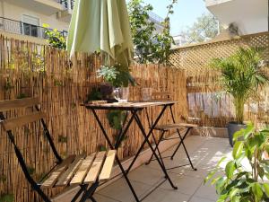 een patio met een parasol en een tafel en stoelen bij Bright Apartment steps from the Sea in Thessaloniki