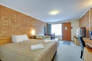 Habitación de hotel con cama y pared de ladrillo en Always Welcome Motel en Morwell