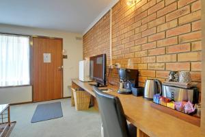 a room with a desk with a computer and a brick wall at Always Welcome Motel in Morwell