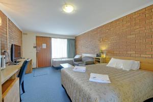 Habitación de hotel con cama y pared de ladrillo en Always Welcome Motel, en Morwell