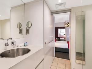 a bathroom with a sink and a bedroom at The Miro Apartments in Brisbane