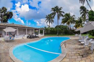 a swimming pool in front of a house with palm trees at Recanto do Aconchego in Porto De Galinhas