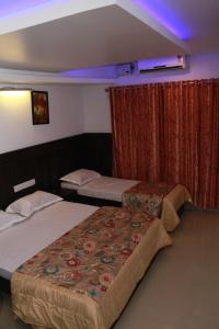 2 camas en una habitación de hotel con luces moradas en FabExpress Le Emrald Residency, en Bangalore