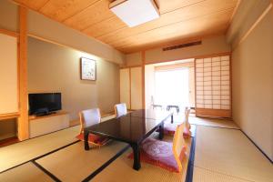 Cette chambre dispose d'une table, de chaises et d'une télévision. dans l'établissement Yorozuya, à Yamanouchi