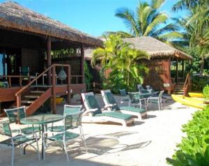 eine Terrasse mit Stühlen, Tischen und einem Pavillon in der Unterkunft Rarotonga Beach Bungalows in Rarotonga