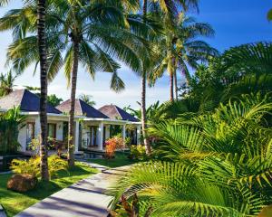 a house with palm trees in front of it at Jivana Resort in Kuta Lombok