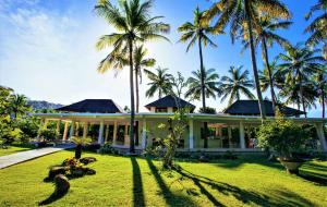 una casa con palmeras delante en Jivana Resort, en Kuta Lombok