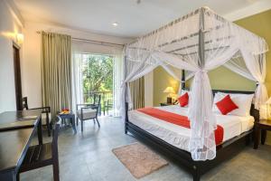 a bedroom with a canopy bed and a desk at Tropical Life Resort and Spa in Dambulla