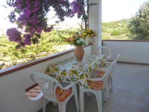 een tafel en stoelen met een vaas met bloemen op een balkon bij House in the most southern point of the island, completely fenced super price. in SantʼAnna Arresi