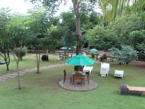 uma mesa e cadeiras com um guarda-sol azul num parque em Thermas Paradise Rio Quente - FR Turismo em Rio Quente