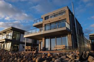a house on the beach with rocks in front of it at Dock 76 Promenade in Olpenitz
