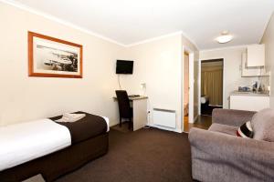 een hotelkamer met een bed, een bank en een bureau bij Ballarat Central City Motor Inn in Ballarat