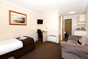 um quarto de hotel com uma cama, um sofá e uma secretária em Ballarat Central City Motor Inn em Ballarat