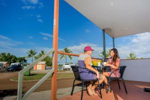 Un uomo e una donna seduti a un tavolo su un portico di Townsville Lakes Holiday Park a Townsville