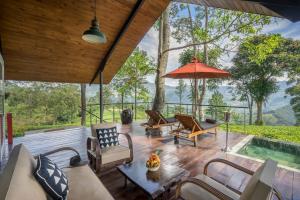 a patio with chairs and an umbrella and a pool at Madulkelle Tea and Eco Lodge in Kandy