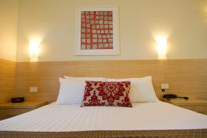 Un dormitorio con una cama con una almohada roja. en The Club Motel and Apartments, en Wagga Wagga