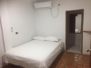 a bedroom with a white bed and a air conditioner at LA CHOZA in Mompos