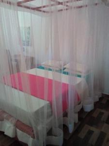 1 dormitorio con 1 cama con cortinas blancas en Gästehaus Isabella, en Beruwala
