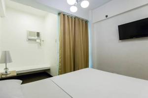 a bedroom with a bed and a tv and a curtain at San Agustin Residences in Manila