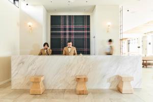 two people standing behind a counter in a lobby at Hotel It Osaka Shinmachi in Osaka