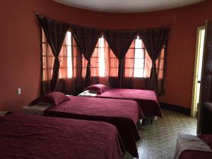 2 Betten in einem Zimmer mit roten Wänden und Fenstern in der Unterkunft Hotel Mayesstic in Guatemala