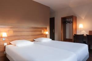 Een bed of bedden in een kamer bij The Originals City, Hôtel Colmar Gare