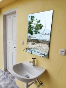 a bathroom with a sink and a mirror and a window at Phinisi Hostel Bira in Bira