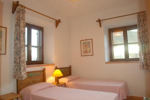 a bedroom with two beds and two windows at Silence and relaxation for families and couples in the countryside of Umbria in Porchiano del Monte +14 photos