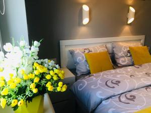 a bedroom with a bed and a vase of yellow and white flowers at APARTAMENT ELEGANCE YELLOW in Rewal
