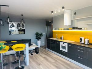 a kitchen with black cabinets and yellow accents at APARTAMENT ELEGANCE YELLOW in Rewal
