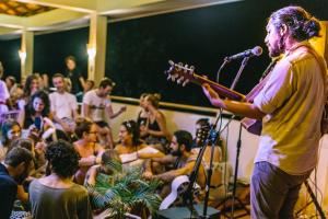 a man singing into a microphone in front of a crowd at Karma Traders Kampot in Kampot +120 photos