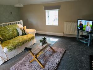 a living room with a couch and a tv at The Old Coach House at Stewton in Louth