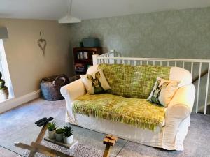 a living room with a white couch with a green blanket at The Old Coach House at Stewton in Louth