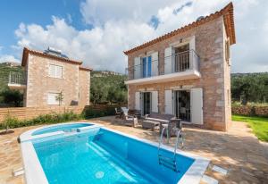 a villa with a swimming pool in front of a house at Amoya villas in Stoupa