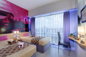 a room with two beds and a desk and a window at favehotel Solo Baru in Solo