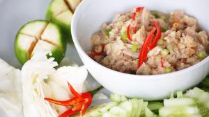 a white bowl filled with food next to some vegetables at Authentic Cambodian Angkor Cottage in Siem Reap