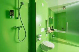 a green bathroom with a shower and a toilet at Hotel Greenrooms in Graz
