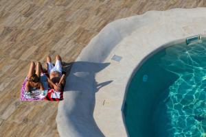 two children laying on a towel next to a swimming pool at Baglio Dello Zingaro in Scopello