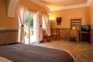 een slaapkamer met een bed, een bureau en een televisie bij Double room in a charming villa in the heart of Marrakech palm grove in Marrakesh